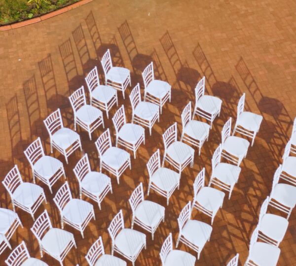 Stock image of a large group of chairs lined up in 5 rows against reddish brown brick walkway