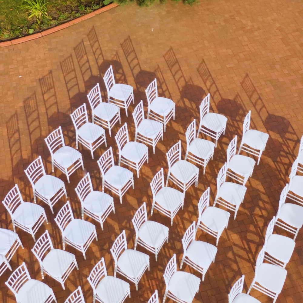 Stock image of a large group of chairs lined up in 5 rows against reddish brown brick walkway